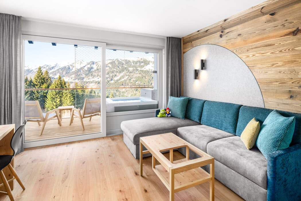 Kinderhotel Allgäuer Berghof – Wohnzimmer der Spass-Suite Froschi mit Blick auf die Allgäuer Alpen
